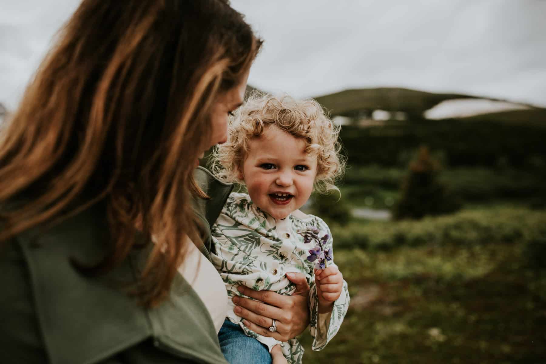 Mother holding baby daughter close, exploring nature, laughing together