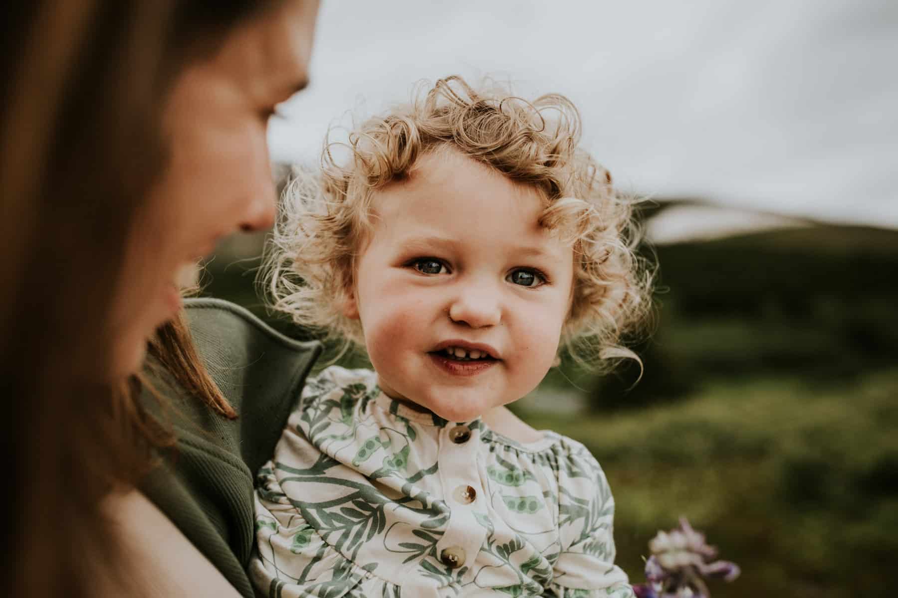 Mother holding baby daughter close, exploring nature, smiling at each other