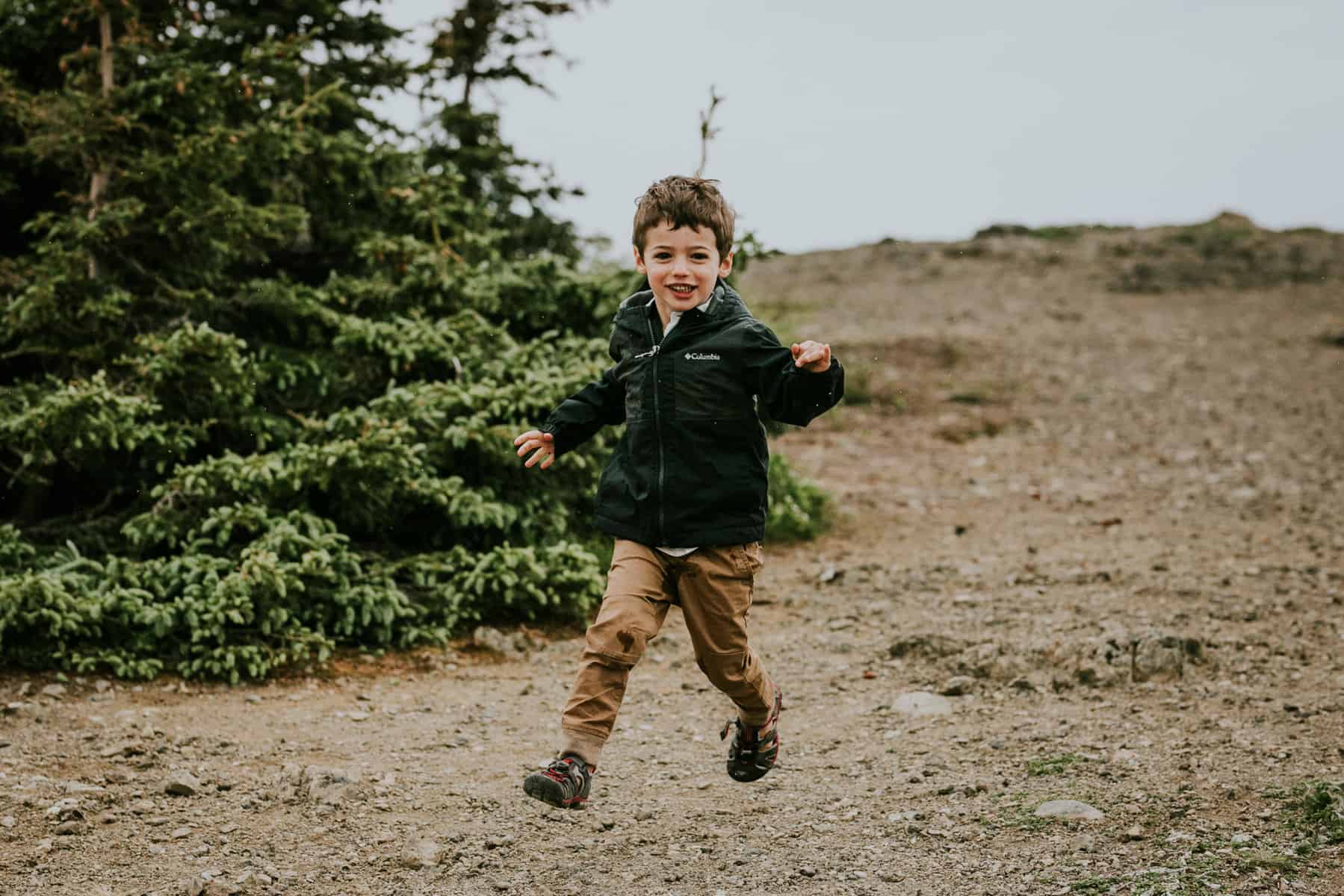 boy exploring nature running down a path laughing