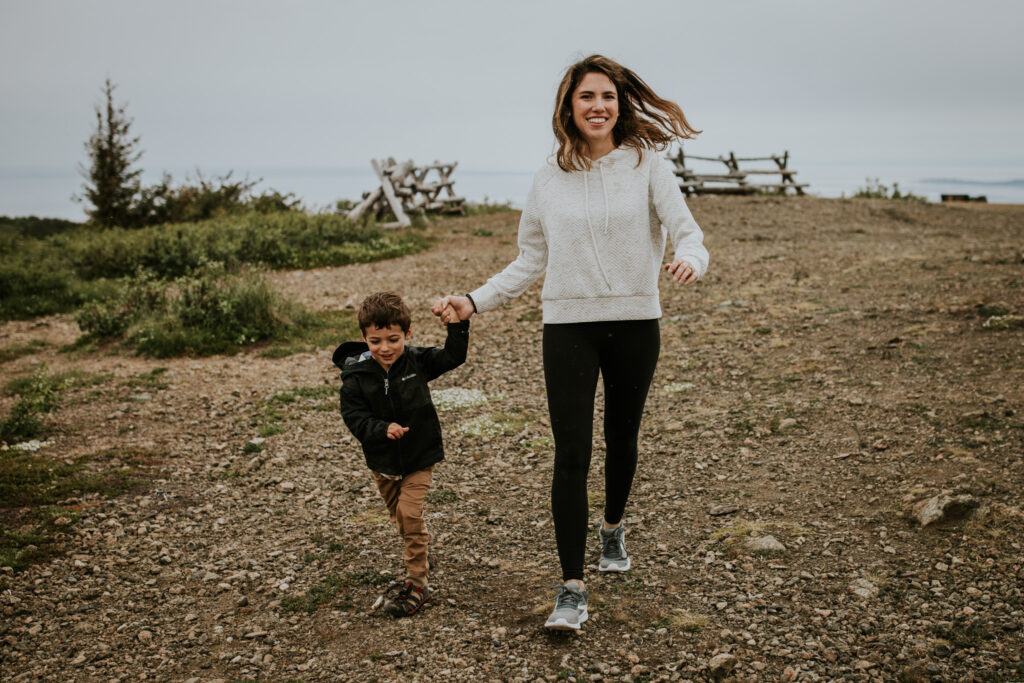 mother and son holding hands running down a path