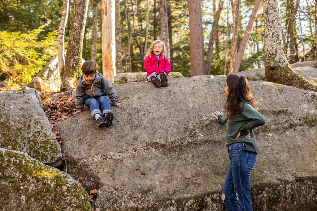 mother on a family hike with two kids, kids sitting on large rock