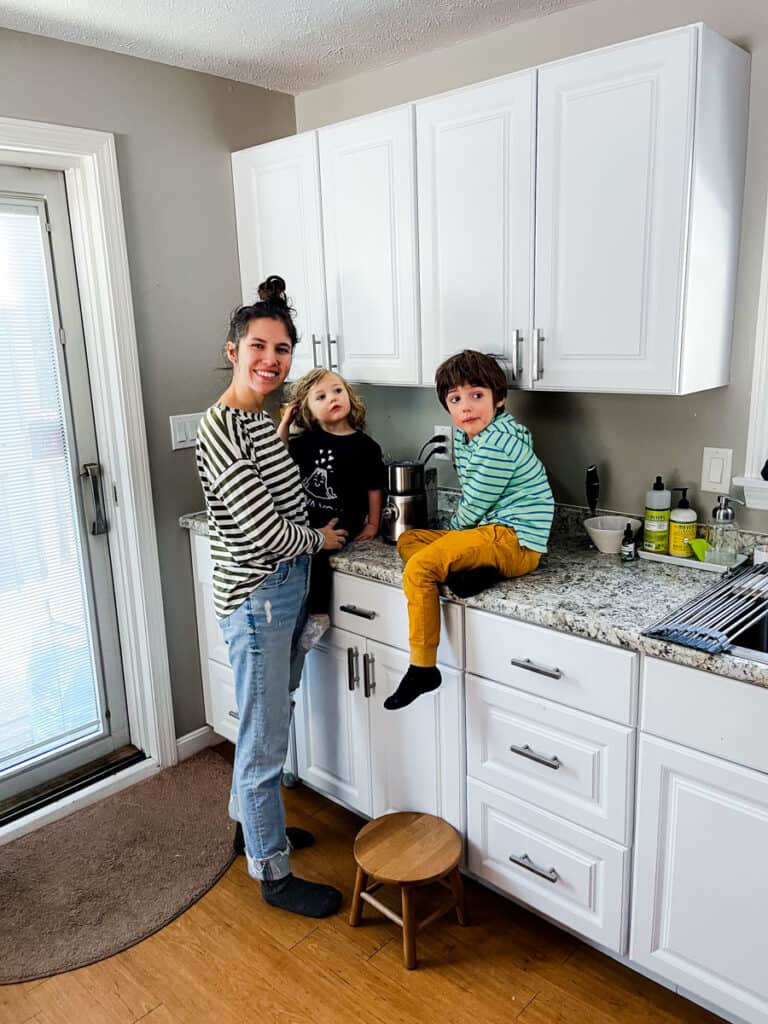 mom standing in kitchen with 3 and 4 year old helping with chores in the kitchen
