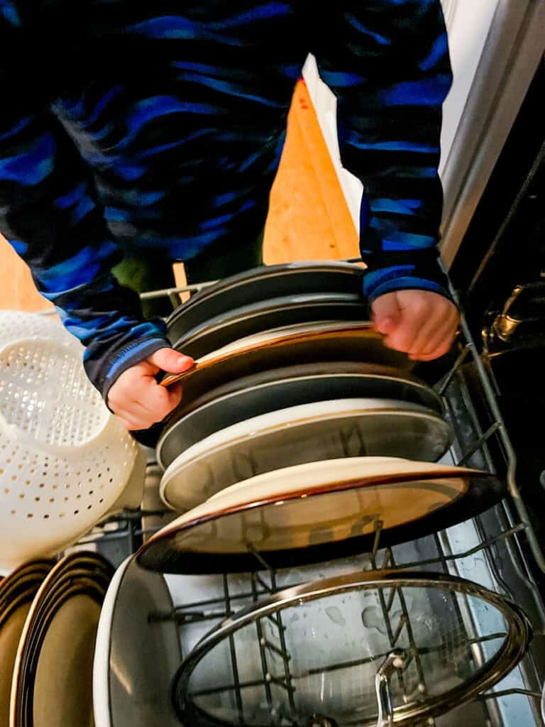 4 year old taking dishes out of dishwasher helping with chore time