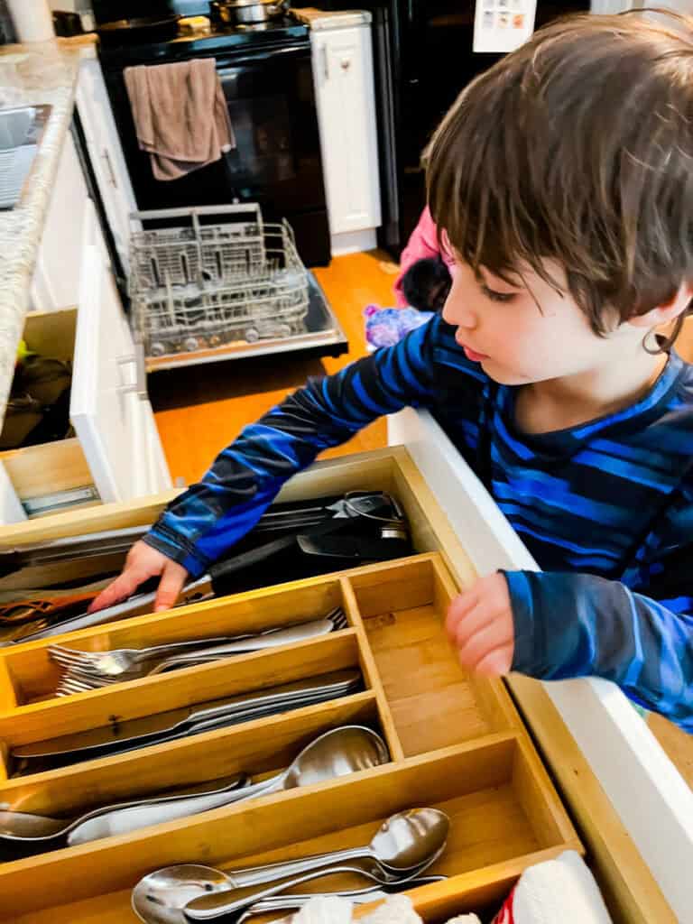 4 year old helping put silverware away during chore time