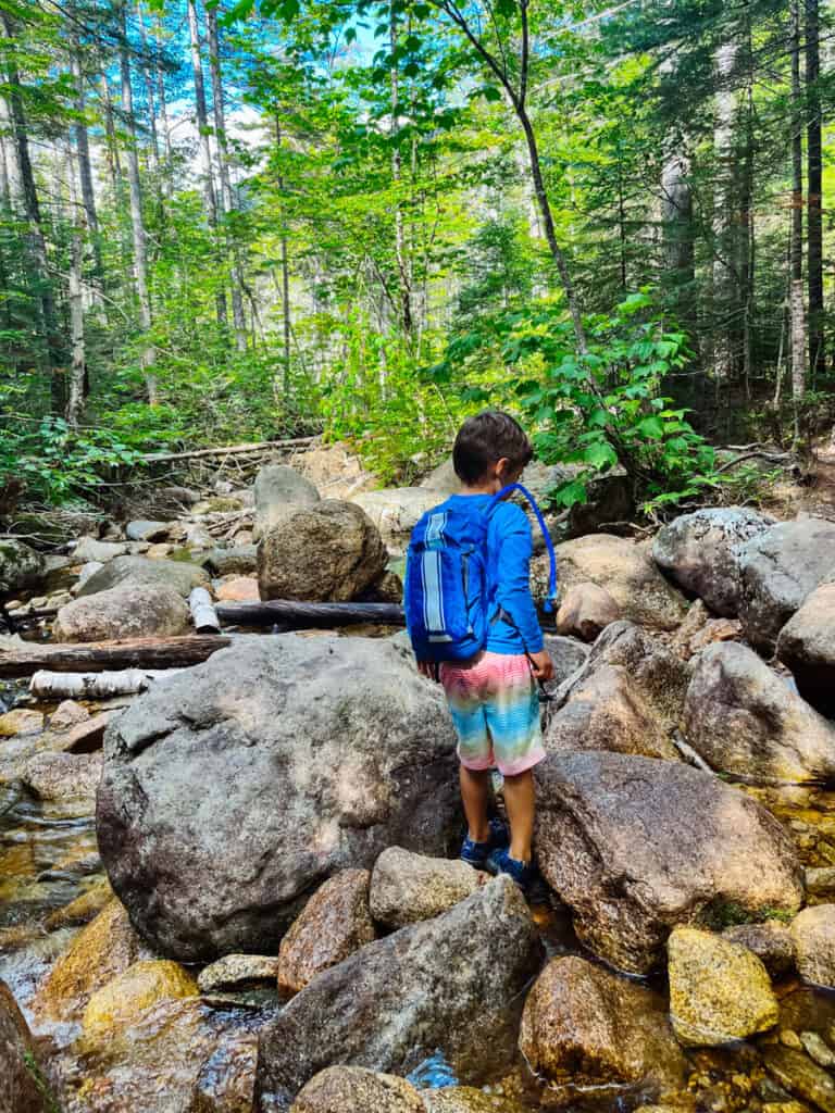 boy hiking during a camping trip with a backpack he got as a camping gift for kids