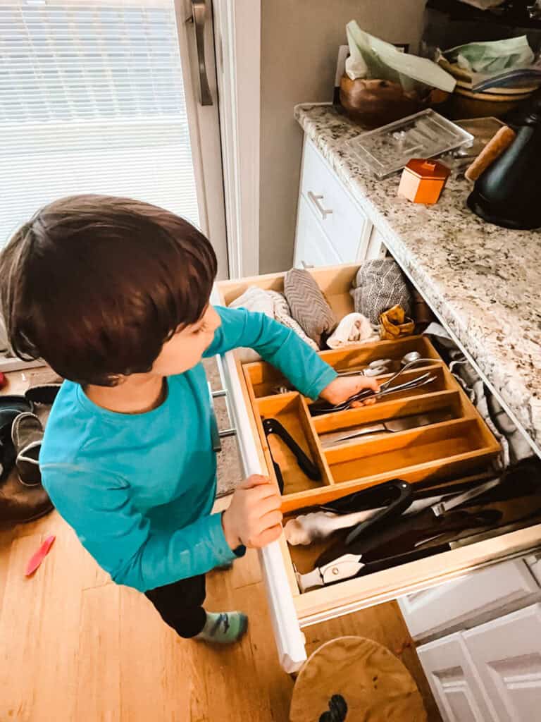 toddler putting away silverware in a drawer