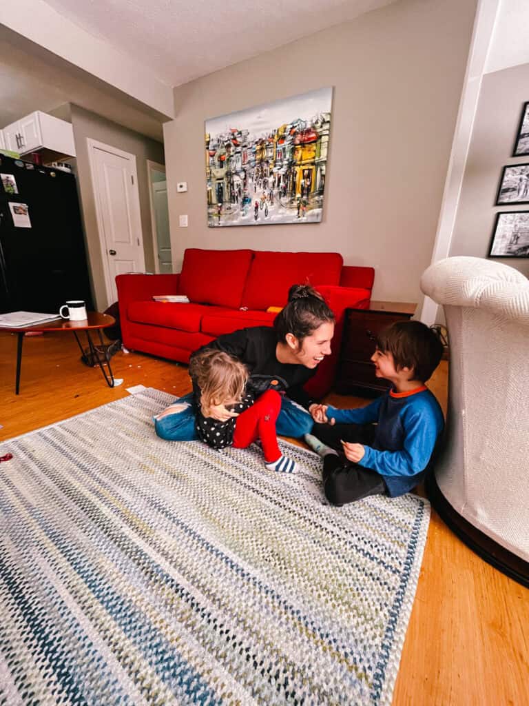 mother and two kids sitting on floor and laughing together