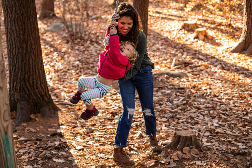 mother helping daughter on rope swing during a family photo session