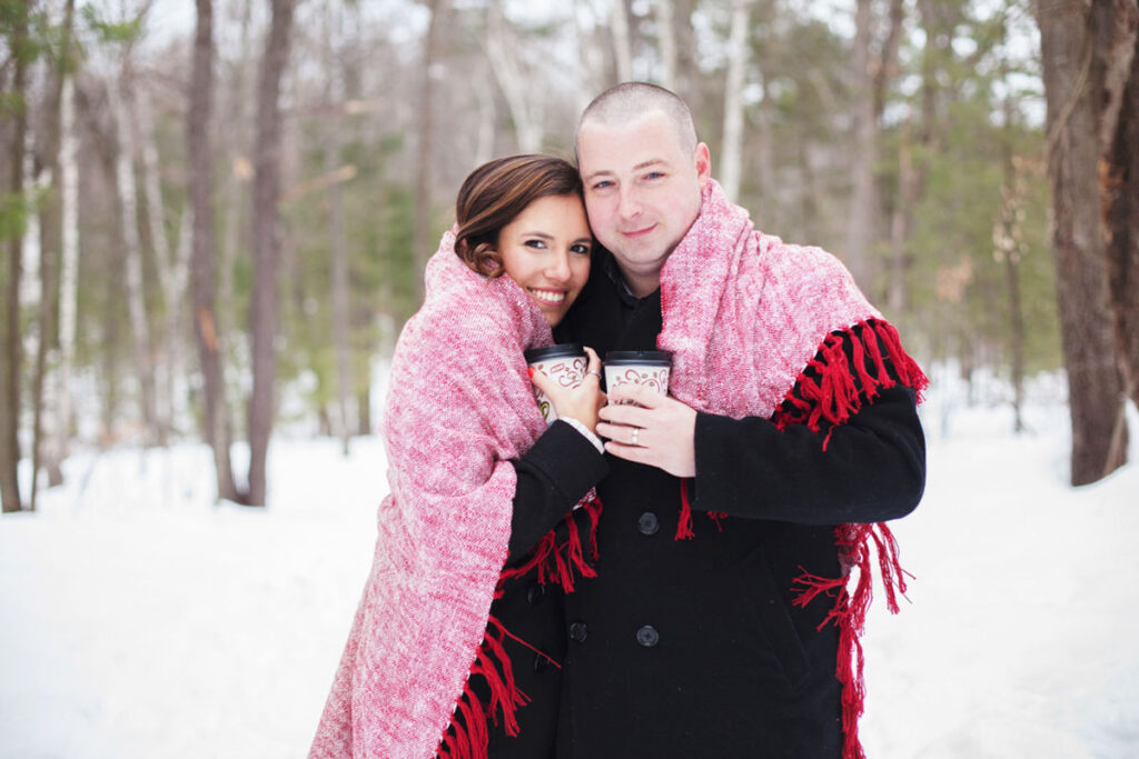 example of family portraits in winter. a couple snuggling with red blanket outside
