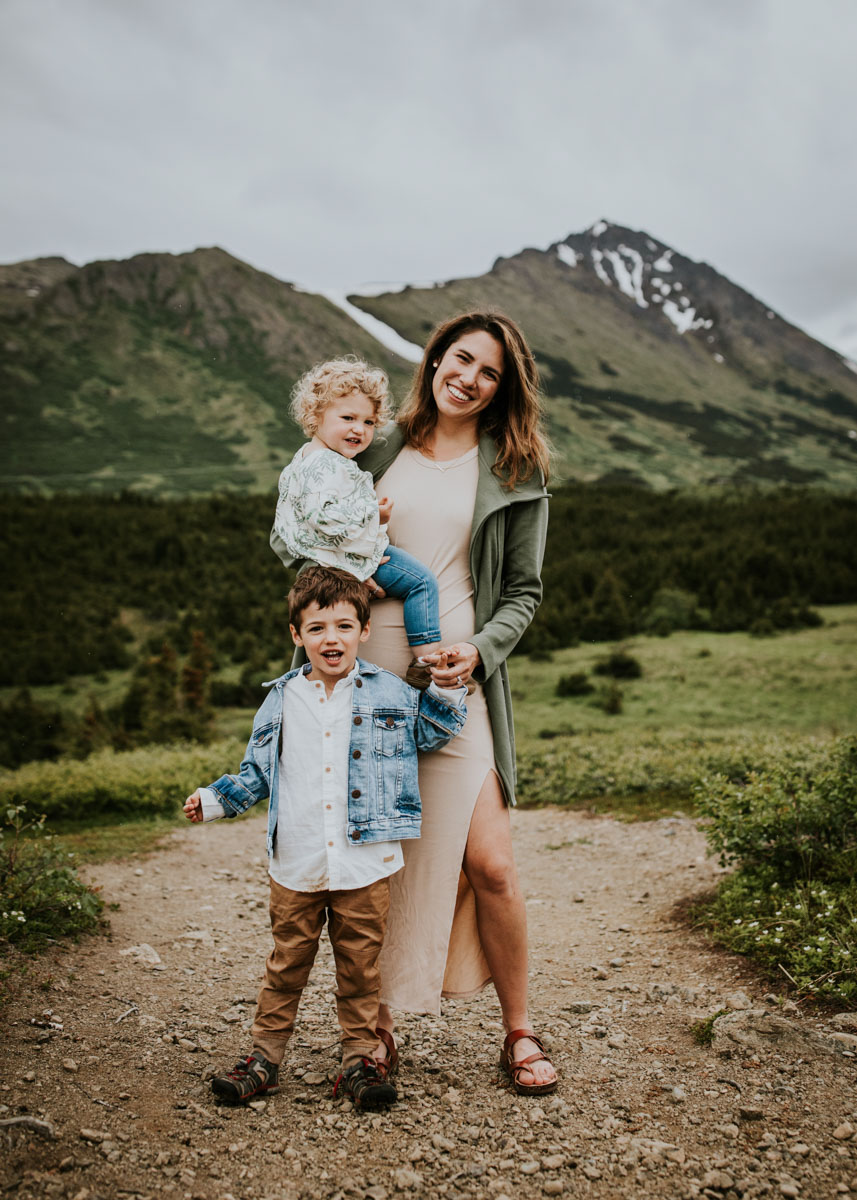 mother holding two kids in the mountains on a family adventure vacation