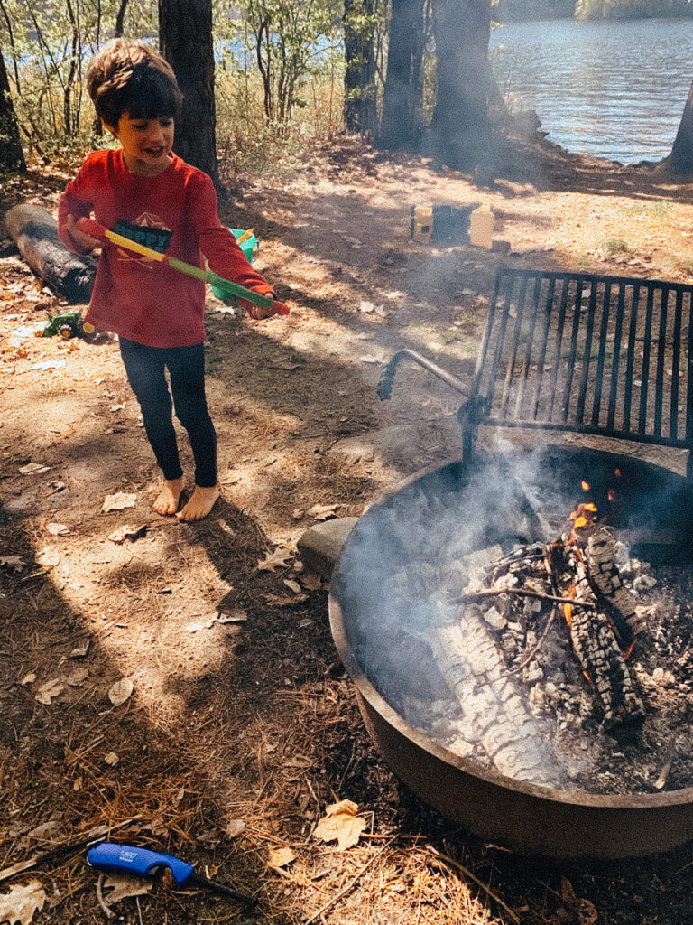 child putting out campfire for fire safety while on a camping trip as a camping activity for families